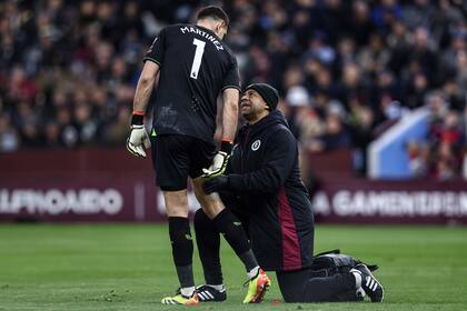 Emiliano Martínez es atendido en su muslo derecho por un integrante del cuerpo médico de Aston Villa, durante el partido con Chelsea