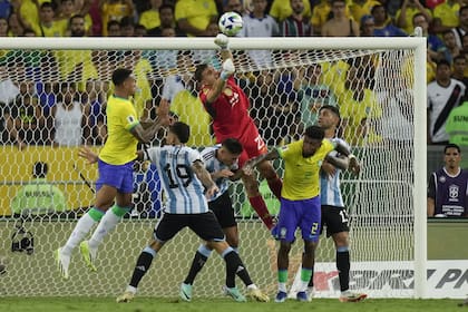 Emiliano Martínez salta para despejar con las manos y Nicolás Otamendi lo cubre ante el salto de un rival; el arquero y el defensor fueron cruciales para el 1-0 de Argentina en Brasil.