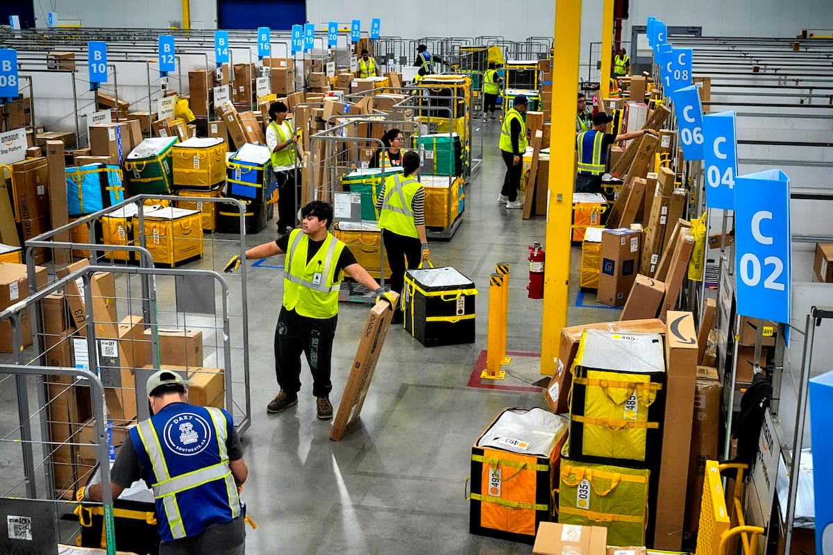 Empleados de Amazon cargan paquetes en carritos antes de colocarlos en camiones para su distribución en el evento anual Prime Day