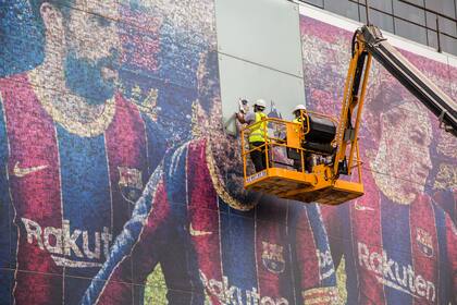 Empleados de Barcelona retirando la imagen de Lionel Messi de la fachada del estadio Camp Nou.