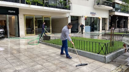 Empleados de la heladería Aversa, en Avenida del Libertador, limpian la vereda tras la inundación