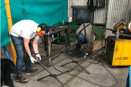 Empleados de la la fábrica realizan uno de los catres para los hospitales de campaña