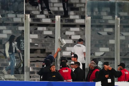 Empleados de seguridad confrontan a algunos aficionados, tras la ruptura de paneles transparentes y la invasión de la cancha durante el partido de la Copa Libertadores entre Colo Colo de Chile y Fortaleza de Brasil, el jueves 10 de abril de 2025, en Santiago (AP Foto/Esteban Félix)