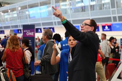 Empleados de servicio al cliente de la aerolínea Delta dan información a viajeros de vuelos retrasados mientras hacen fila en el aeropuerto Internacional Minneapolis/St. Paul luego que una actualización de software defectuosa causó estragos tecnológicos en todo el mundo, el viernes 19 de julio de 2024, en Minneapolis. (AP Foto/Adam Bettcher)