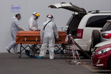 Empleados funerarios trasladan un cuerpo en el Hospital San José, en Santiago