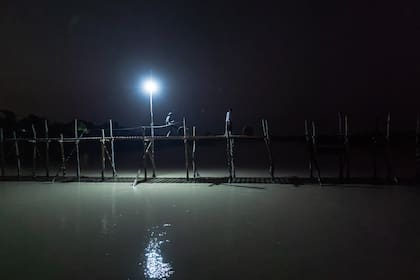 Empujando barriles de combustible a través de un pequeño puente por la noche para abastecer a aldeas remotas. La oscuridad ofrece cierta cobertura del ejército de Myanmar