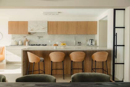En alacenas y debajo de la barra se trabajó con un varillado artesanal, en contraste con el color crema del resto del mobiliario. “La idea era lograr un diálogo con los pisos del living, que visualmente haya una unión”. Banquetas en hierro negro y madera, traídas de España.