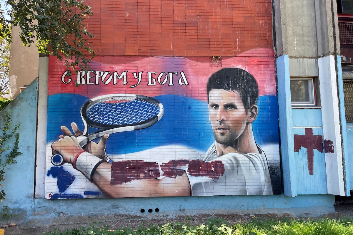 En Banjica, el barrio en el que se crió Djokovic, un mural de Nole empuñando la raqueta con la mano izquierda (el tenista es diestro) y la frase en cirílico que se traduce “Confiamos en Dios”