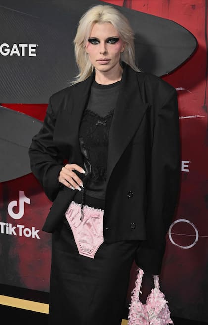 En cada lugar en el que se presenta, Julia Fox llama la atención por sus inclasificables looks. En esta oportunidad, apareció en la avant premiere de El cuervo con un detalle que no pasó desapercibido: llevó un sobrio blazer negro, una pollera de satén, una camiseta gris y, sobre la falda, una prenda interior rosa