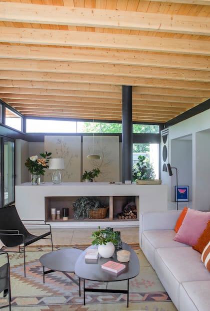 En casa de los arquitectos Agustina García Albarido y Martín Bayley Bustamant, el living-comedor queda parcialmente dividido por el hogar construido en obra, que se funde con los muros y el piso.