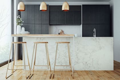 En combinación con una isla íntegramente revestida en mármol de Carrara, una barra con patas de hierro pintadas en blanco y tapa de madera clara. Las banquetas en color cobre le dan brillo y sofisticación al espacio