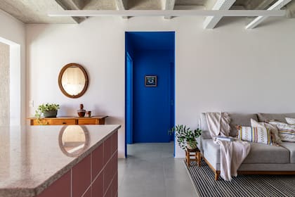 En contraste con el rosa de la cocina, el hall de acceso a los ambientes privados se tiñó de un azul profundo.