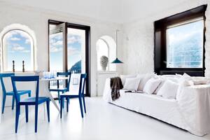 En el ambiente más grande, que reúne living y comedor, se recuperaron las ventanas con arco originales, en una de las cuales se destaca un dúo de candelabros de cerámica (Michele Pagano).