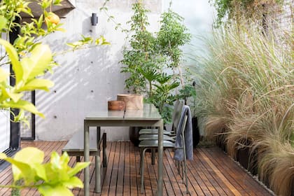 En el amplio balcón, juego de mesas y bancos en chapa verde pintada al horno (Estudio Te). Macetas (Urban Pots). Entre las especies plantadas en el balcón hay gramíneas, jazmines de leche y aromáticas.