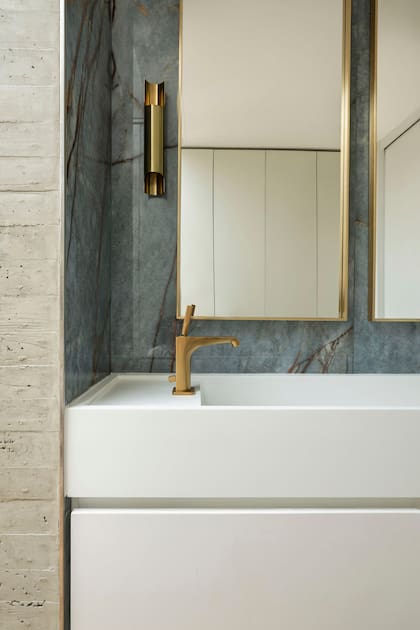 En el antebaño, porcelanato italiano Florim ‘Heritage Azure Glossy’ con grifería Axor ‘Citterio Oro’ (todo de SBG). Aplique ‘Italy’ de aluminio (Fábrica de Luz) y espejos enmarcados (Tulia Desarrollos).