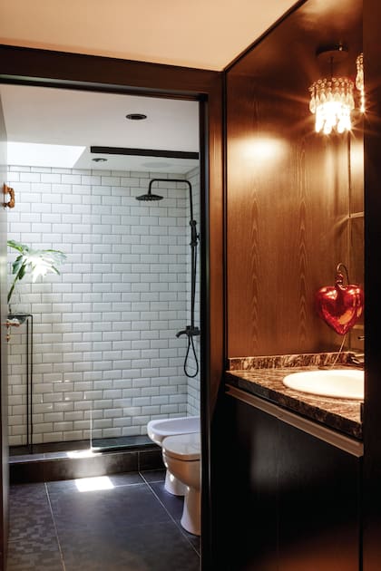 En el antebaño, un corazón de vidrio traído de México. Artefactos de la línea ‘Sense’ (Roca), revestimiento de cerámicos ‘Subway’ (Barugel), fotos enmarcadas y pie de hierro (Iron Home).