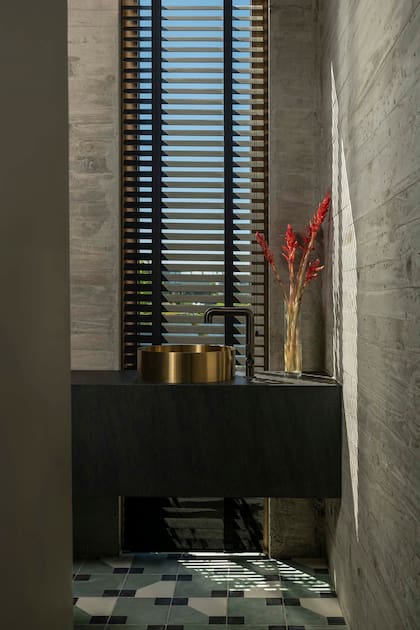 En el baño con piso calcáreo (Noi Estudio), bacha ‘Brera Oro’ con grifería IB ‘Bold Lever’ (todo de SBG) y mesada (De Stefano), trabajada por Mármoles Antón. Cortina americana en aluminio de Hunter Douglas (Florencia Franchini).