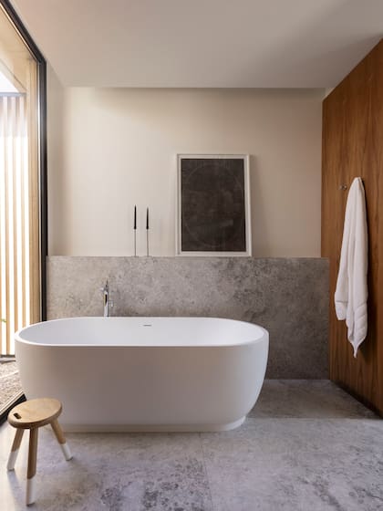 En el baño de la suite, un antepecho de mármol da apoyo a la obra de Andrés Latorre (Diderot.art) junto a la bañadera exenta en Solid Surface (De Stefano). Banquito ‘Oriente Milk’ (Krethaus).