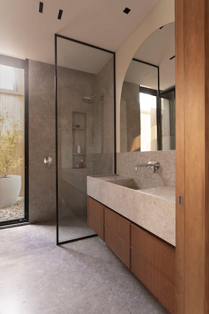 En el baño, mesada de mármol ‘Tundra Grey’ (De Stefano), grifería (Hansgrohe) y vanitory de madera (De Otro Tiempo).