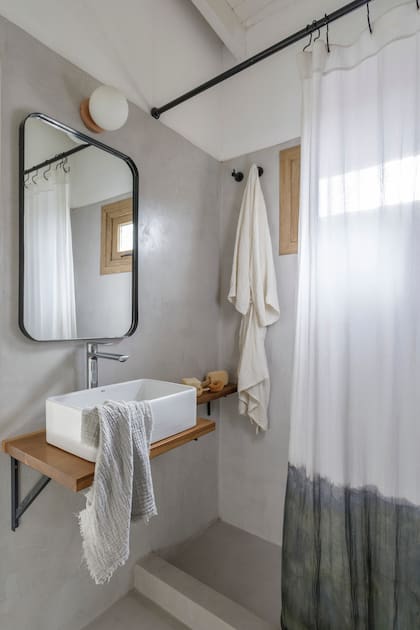En el baño, piso y revestimiento de cemento alisado (Miracema). Mesada de madera con bacha de apoyo (Rocca), grifería (FV), toalla de mano (Lote Propio). Espejo (Za Mobiliario Industrial), lámpara (Dimm), cortina (Maru Bardó).