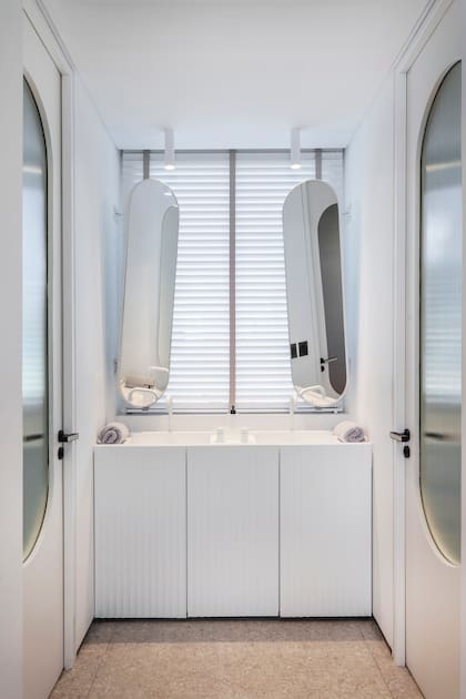En el baño principal, mesada de Purastone ‘Blanco Nube’ (United Stone) y mueble laqueado blanco acanalado.