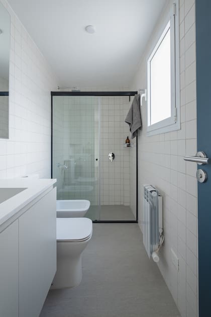 En el baño, todos los muros se revistieron con cerámicos ‘QZ’ blancos satinados, de 10x10cm (Modo M). Mampara ‘Línea 4000’ (Glassic). Vanitory de melamina ‘Gris Ceniza’ (Faplac) con mesada de Purastone ‘Blanco Cana’ (Marmolería Gaona). Para el piso –incluido el del box de ducha–, porcelanato ‘Urban Light Grey’ de Vite (SBG). Sanitarios ‘Temple’ (Ferrum).