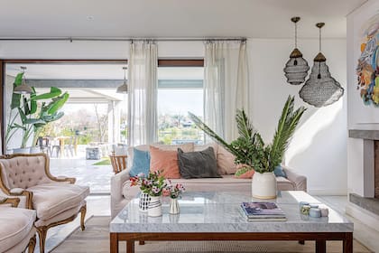 Mesa baja de incienso con tapa de mármol de Carrara y butacas antiguas con capitoné (todo de Constanza Serantes). Lámparas de techo (Pottery Barn).