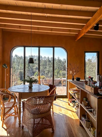 En el comedor, mesa antigua reciclada y sillones de mimbre. Ventanal con herrería hecha a medida