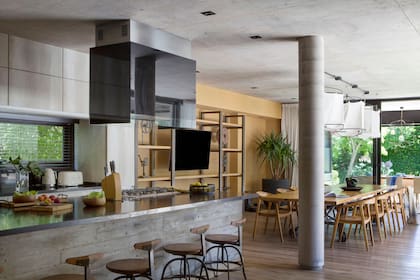 En el comedor, mesa de 4 metros, sillas de teca y mueble de TV de hierro y pino canadiense (todo de Hugo Tonti). Lámparas ideadas por los dueños, con estructura de hierro realizada por Tonti. Para la pared de ese sector eligieron un entelado de arpillera (Oscar Favre).