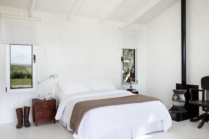 En el cuarto de la cabaña basta con las visuales del campo y la laguna, y la cama cómoda al abrigo de una salamandra de hierro.