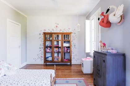En el cuarto de las chicas, placard comprado en un remate enmarcado con motivo floral pintado sobre la pared. La ropa de cama es de Ikea.