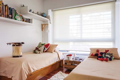 En el cuarto de los varones, camas antiguas de madera barnizada, fundas de acolchado teñidas (Estévez) y cajón para juguetes.