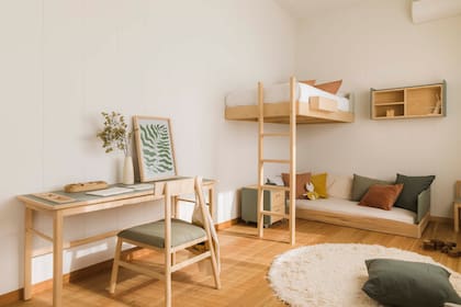 En el cuarto infantil, cama amurada, cama baja con almohadones, cajonera con ruedas, escritorio, silla y mesa de luz (todo de Ukelele). Alfombra (Mercado Libre). Cuadro (Marcos Más Arte Decó). Las paredes están revestidas con tableros de MDF pintados de blanco.