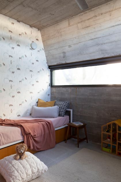 En el cuarto infantil, el empapelado de colores sutiles se adapta al singular ángulo del techo. Manta y almohadones (Lote Propio).