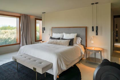 En el cuarto se combinan las mesas de luz laqueadas (Quintana Casa) y banqueta de aluminio (Harturo) con piezas hechas a mano como las lámparas de madera torneada (Fábrica de Luz) y alfombras tejidas a mano (Elementos Argentinos).