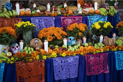 En el Día de Muertos, las familias mexicanas hacen ofrendas y altares decorados con flores, papel picado, calaveras de azúcar, pan de muerto, mole y platos de comida (Fuente: Nick Agro)
