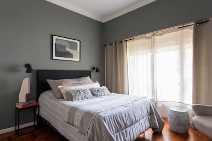 En el dormitorio de Rodrigo, paredes en tono ‘Thunderous’ (Sherwin Williams), acolchado (Arredo), pie de cama (Zara Home), almohadones (Teodolina Deco), mesas de noche (Ziba), obra de cerámica artesanal (Hábitat Concept). Cortinas (Ikea).