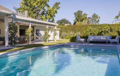 En el extremo de la pileta que tiene un gran escalón bajo para tomar sol en el agua, juego de muebles de exterior con colchonetas impermeables.