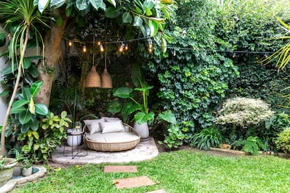 En el fondo del jardín, camastro, almohadones y mesa de arrime (Increa); jarra de vidrio (CB2) y vasos (Binah Deco). Macetas (Ciudad Naturaleza). Lámparas colgantes (Compañía Nativa).