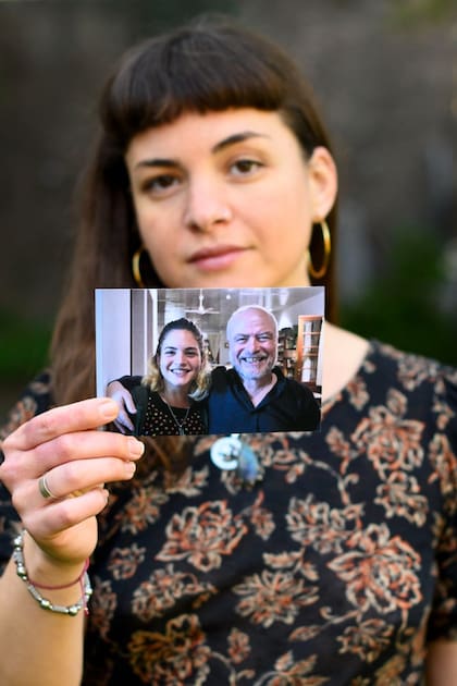 En el jardín de su casa en Rosario, Julia sostiene una foto junto a su papá, Adrián.