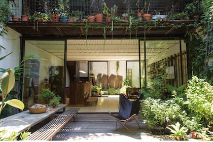 En el jardín delantero, piso de durmientes de quebracho, mesa larga de madera reciclada de pino Brasil, bancos ‘V’ de varillas y una silla BKF negra (todo de Net Muebles). El paisajismo, de especies autóctonas, estuvo a cargo de Par Paisaje, el estudio que la dueña de casa tiene junto a Violeta Ossa