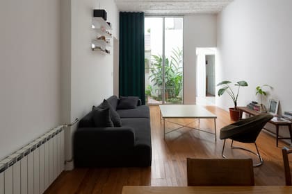 En el living-comedor, sofá (Helmut) y ratona hecha con una estructura de acero recuperada y tapa de MDF enchapado en color hueso. Sillón circular (Un Lugar Así). Alrededor de la mesa de comedor (BLVD), sillas de madera (La Base).