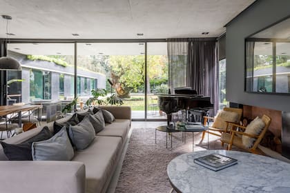 En el living con orientación Norte, sillón, mesa baja con tapa de mármol y mesas auxiliares diseñados a medida por Villanueva y Cseh. Piano de cola, que suele tocar uno de sus hijos.
