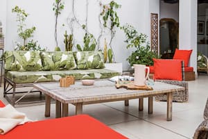 En el living exterior, sofá y trío de sillones de ratán (Ikea) con almohadones hechos a medida (Anne y Flor, Deco en Telas). Una vieja tabla de madera traída desde Francia acompaña las reuniones entre amigos.