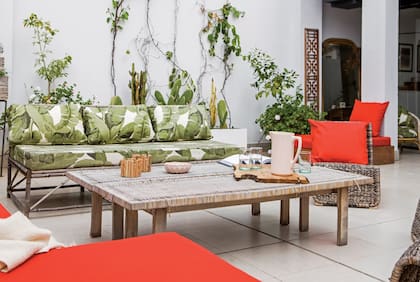 En el living exterior, sofá y trío de sillones de ratán (Ikea) con almohadones hechos a medida (Anne y Flor, Deco en Telas). Una vieja tabla de madera traída desde Francia acompaña las reuniones entre amigos.
