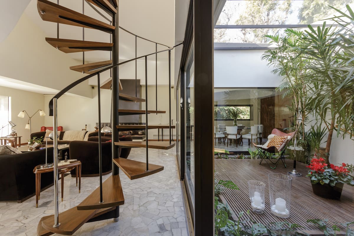 En el living se reconstruyó el piso monolítico de escallas de mármol y en el jardín de invierno se hizo el deck igual al existente pero con varillas de madera más finas y terminación es plastificada. Silla 'BKF' y mesa de fumador de los años '50, compradas en una compra-venta en Uruguay.