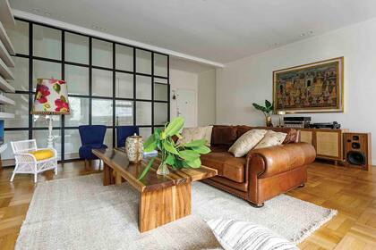 En el living, sillón de cuero heredado. Alfombra tejida a mano (Awanay). Sillones retapizados en pana azul y fundas de almohadones (todo, De Levie). Lámpara de pie heredada.