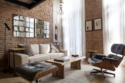En el living, sofá (Mar Deco), mesaratona de petiribí macizo y mesa de apoyo en hierro y madera (Manifesto). Poltrona Eames Lounge, alfombra (Mihran) y espejo envejecido diseñado por la interiorista.