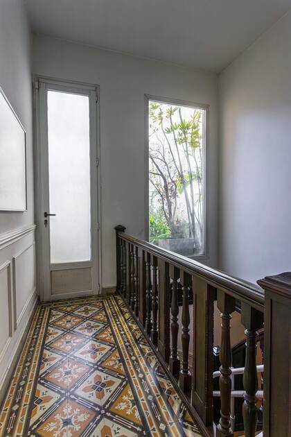 En el nivel superior, la escalera de madera conduce a un pasillo que conserva los calcáreos originales de la casa. Junto a la puerta agregaron un paño fijo hacia el exterior: además de ganar luz, de noche les permite apreciar la luna desde planta baja.