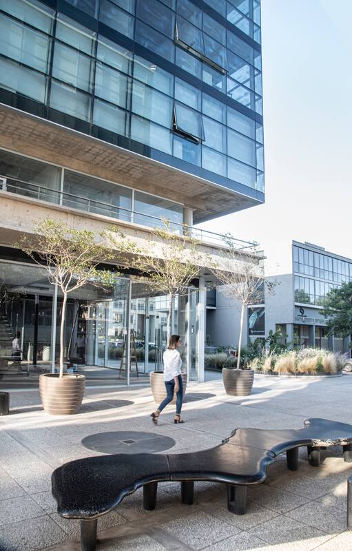 En el Patio Central, el espacio entre los dos edificios, se generó un lugar de espera y de descanso, con bancos “Encuentros” de formas orgánicas, bancos “Rehué” altos y bajos, y maceteros “Canasto”, todos diseños del Estudio Cabeza, con Lagerstroemia indica equilibrando la composición.